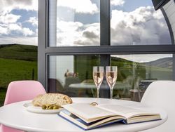 Prosecco and book on table with view outside glamping pod