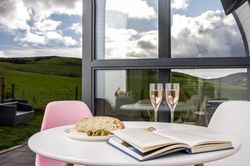 Prosecco and book on table with view outside glamping pod