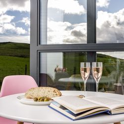 Prosecco and book on table with view outside glamping pod