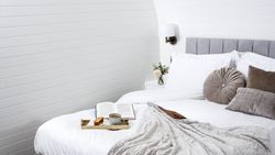 Tray of tea and cake with a book on bed with grey cushions