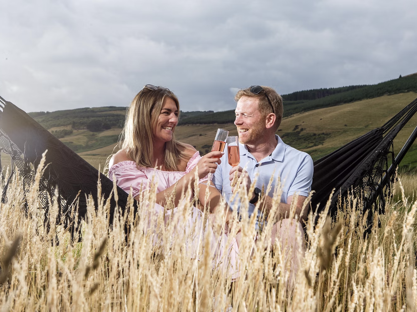 Couple sat in hammock with drinks
