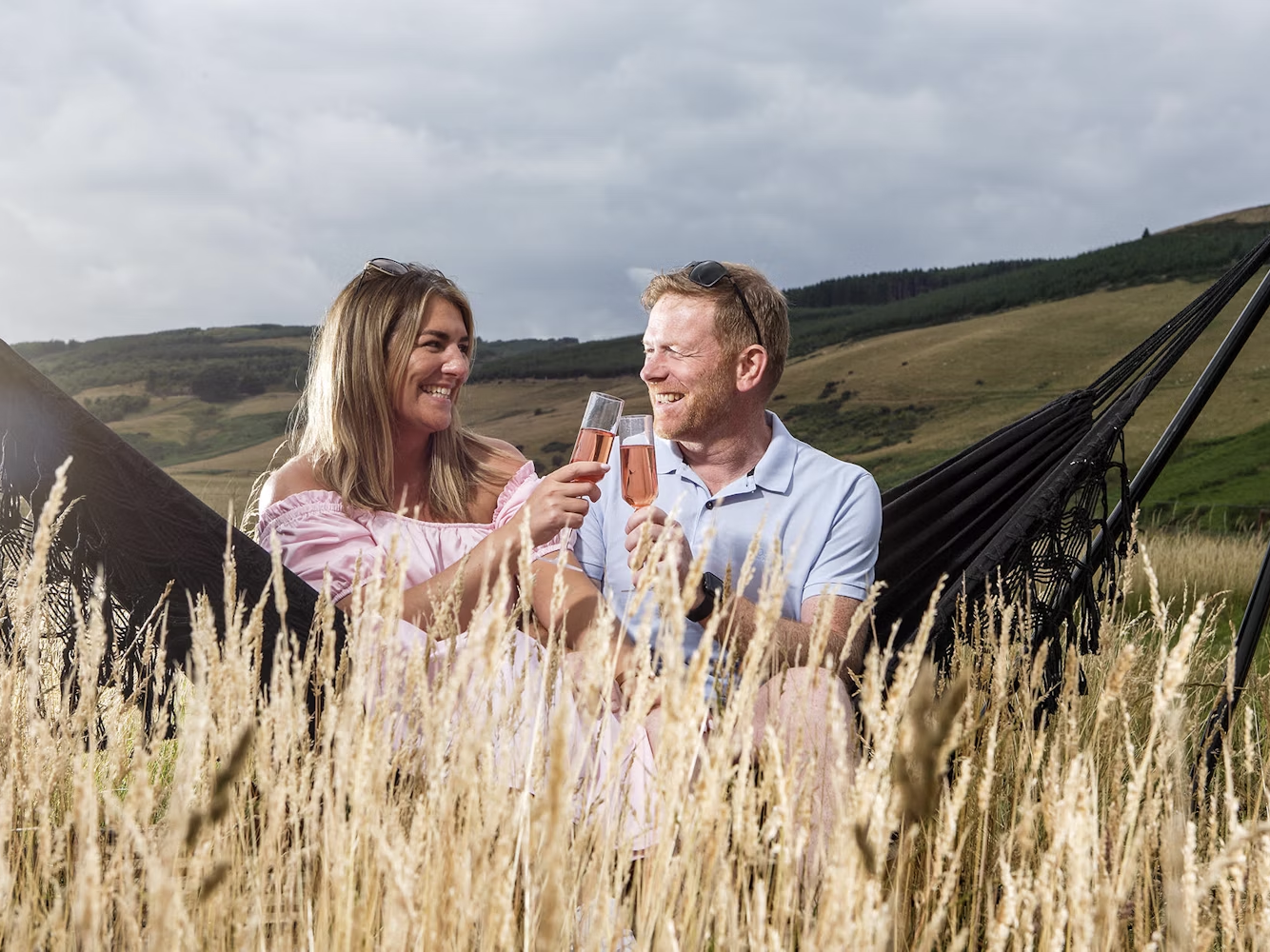 Couple sat in hammock with drinks
