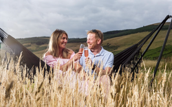 Couple sat in hammock with drinks