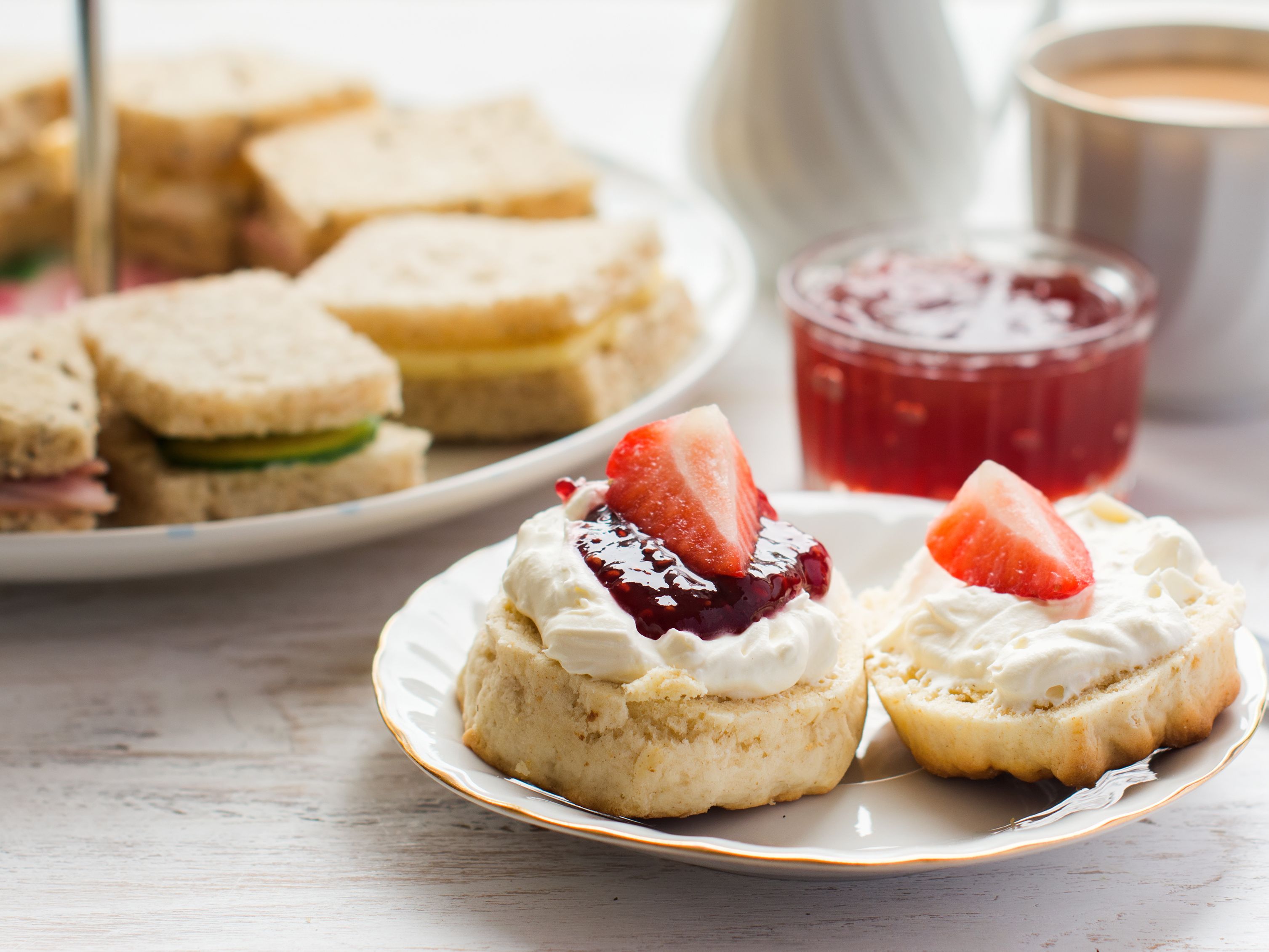 Sandwiches on afternoon tea stand with scones and cup of tea