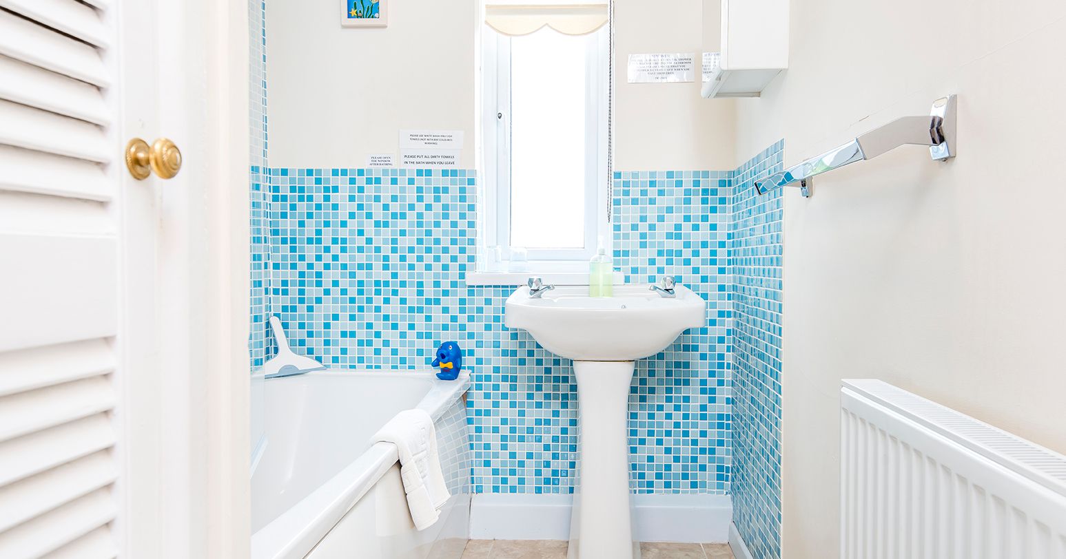 Bathroom in Cothi Cottage with bath and bright blue tiles
