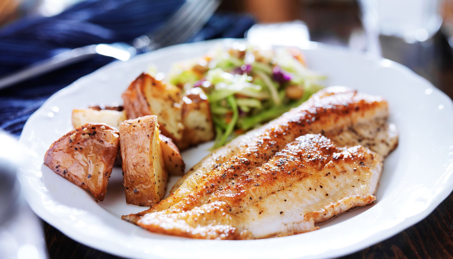 A slice of fish with crispy potatoes served with a side salad