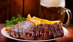 steak and chips on a plate in front of a pint of lager