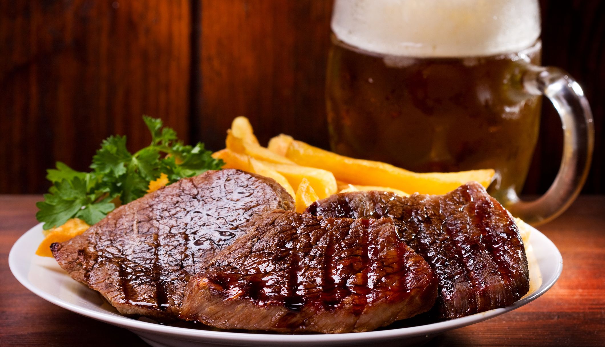 steak and chips on a plate in front of a pint of lager