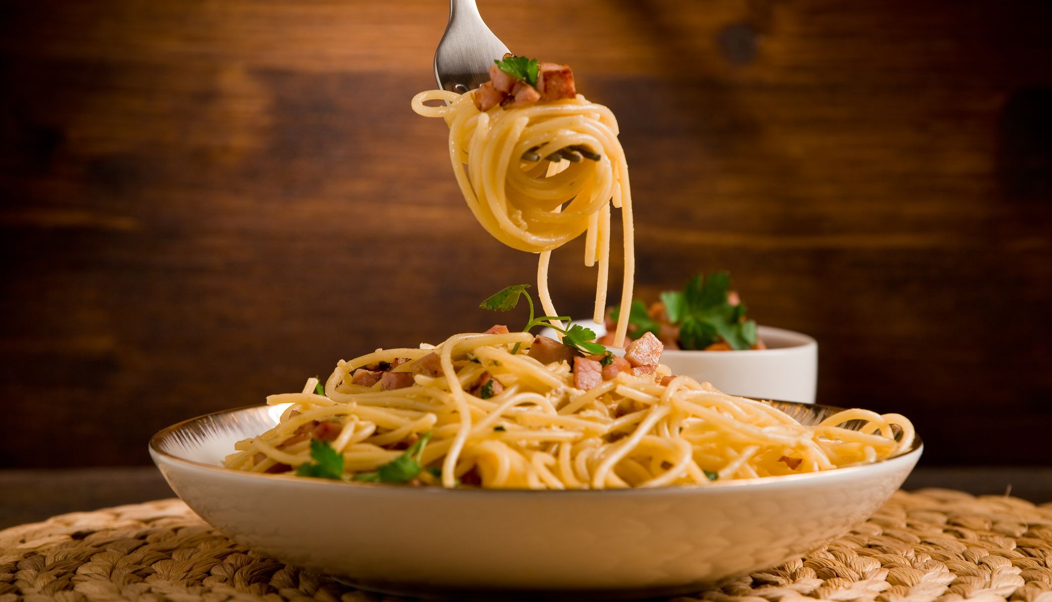 Spaghetti carbonara with a fork lifting the pasta out of the bowl
