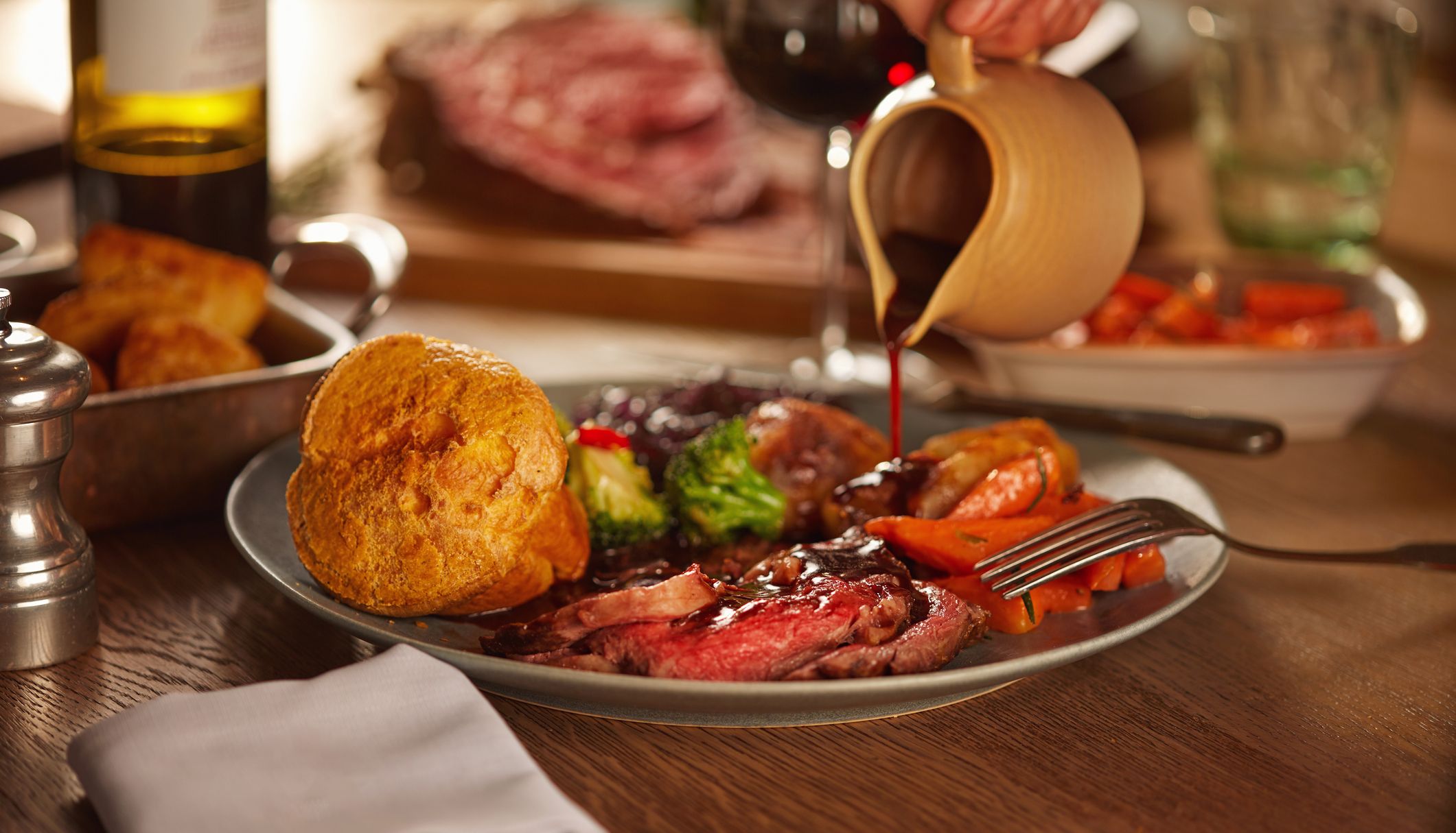 Roast dinner with someone pouring gravy over the top of the yorkshire pudding