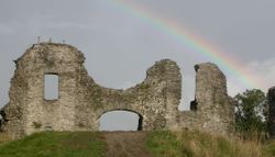 Castle ruins with a grey sky and part of a rainbow above