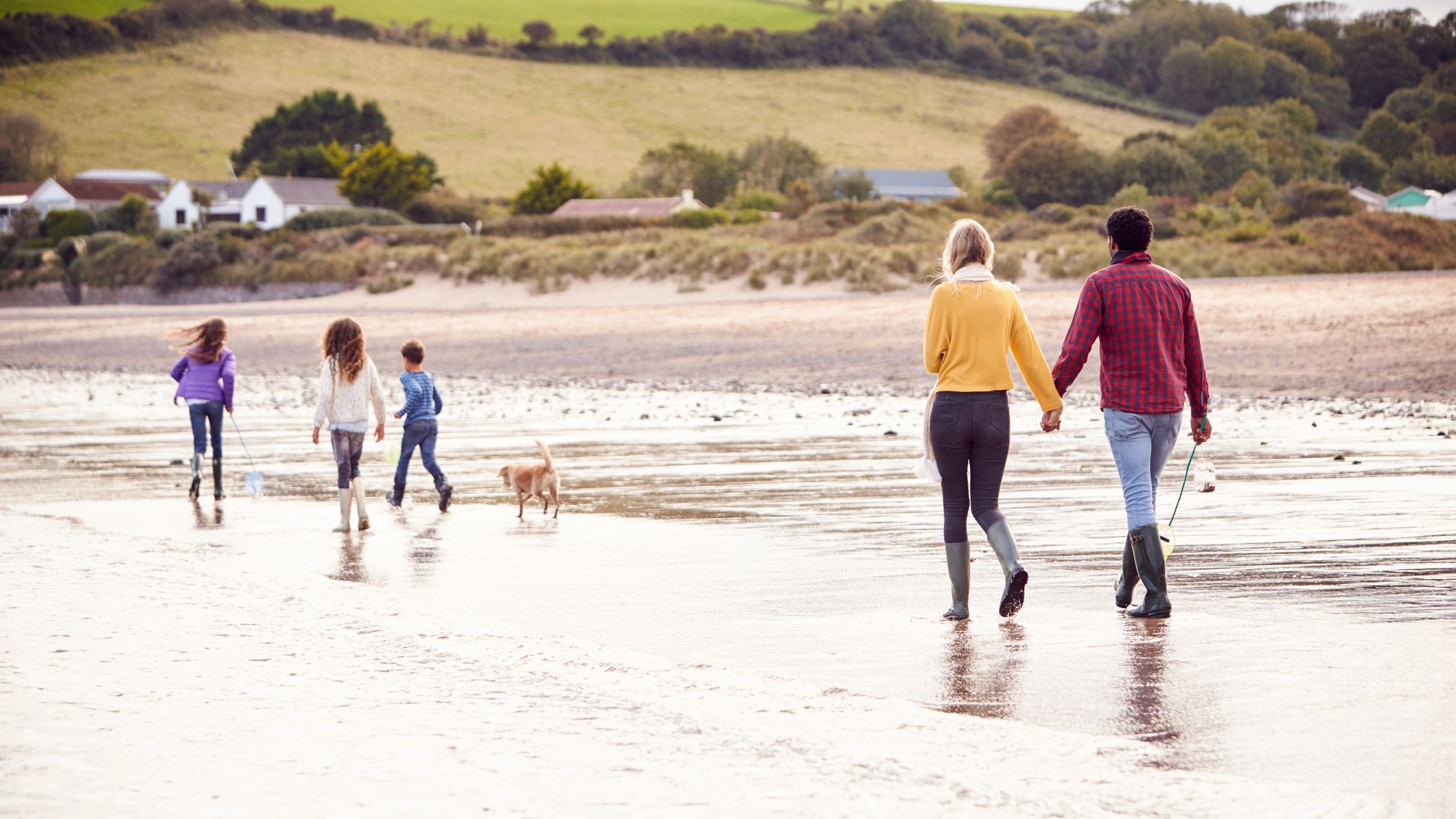 view of a family walking along a beach in winter with their pet dog