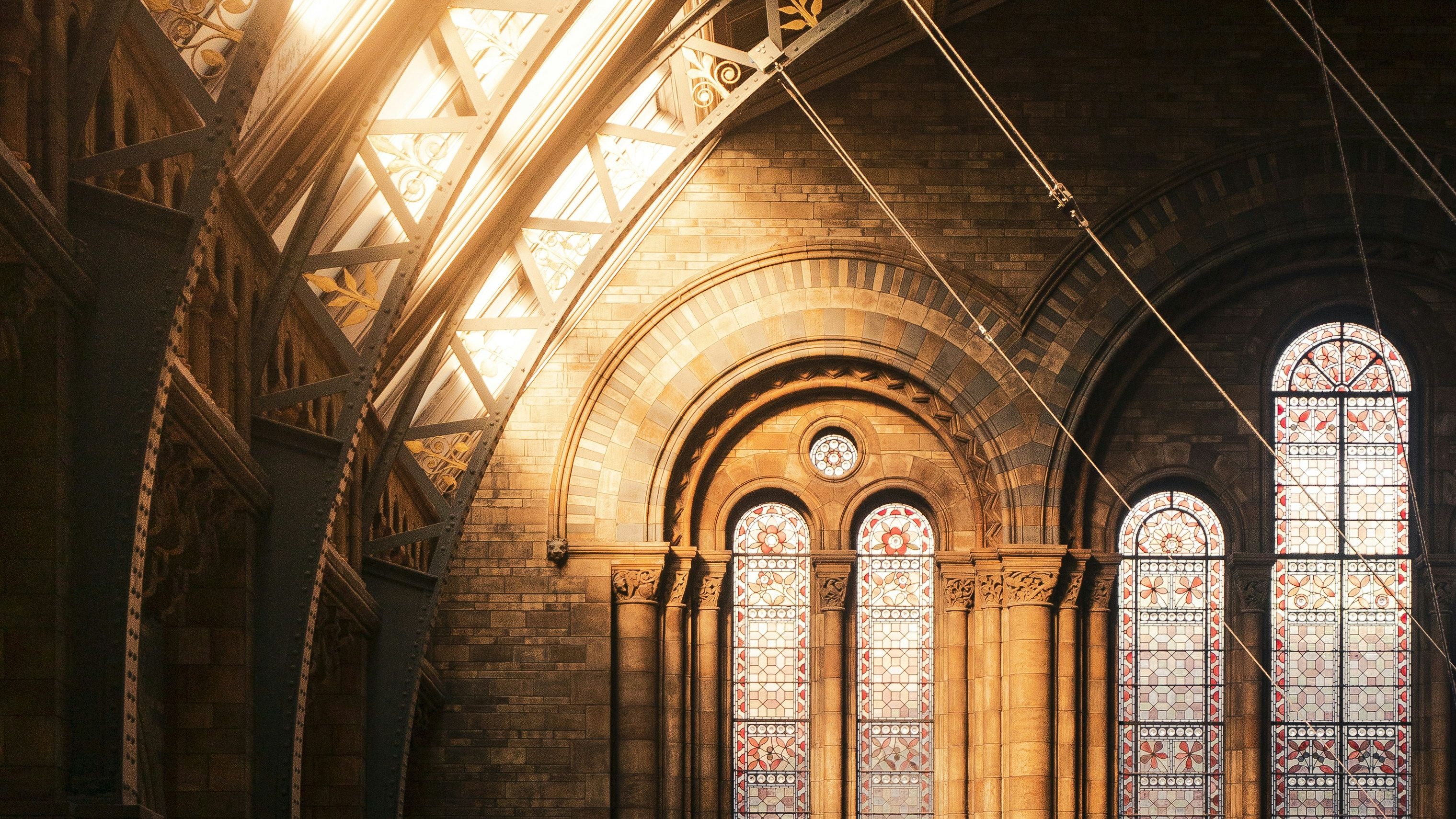 Sunlight streaming through skylights above stained-glass windows in an ornate historic hall