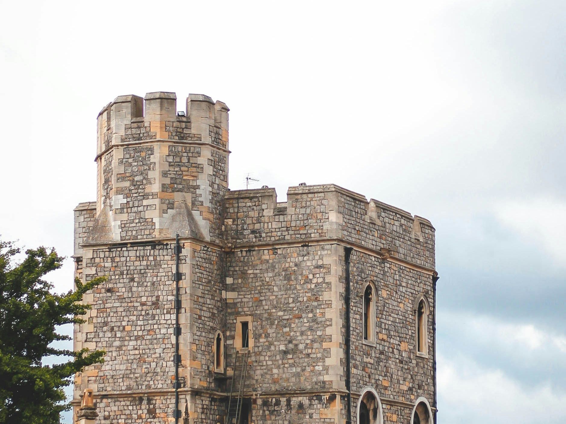 Stone castle tower with crenellations under a cloudy sky