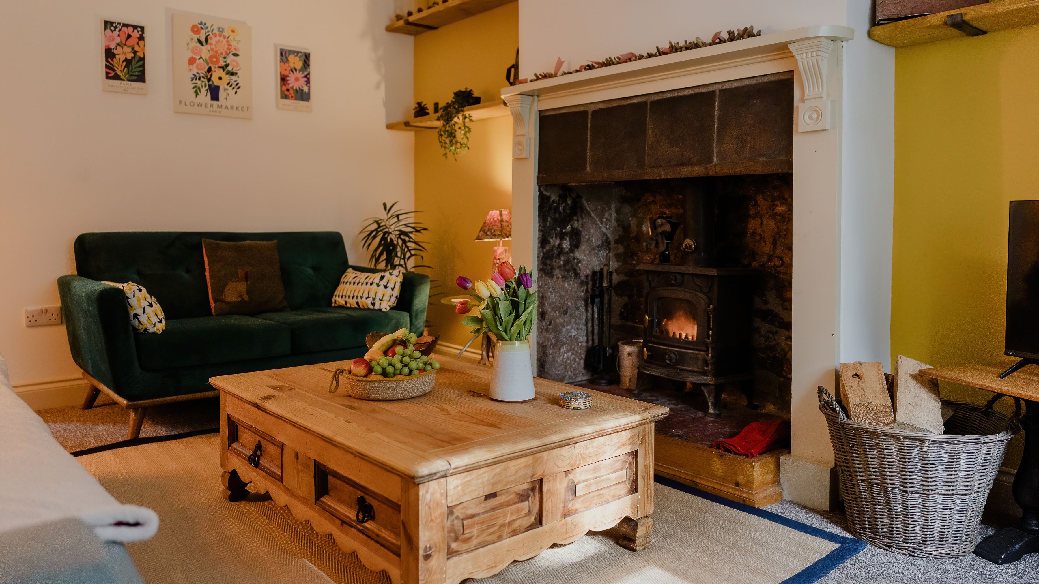Cosy living room with green sofa, wooden coffee table and lit wood-burning stove