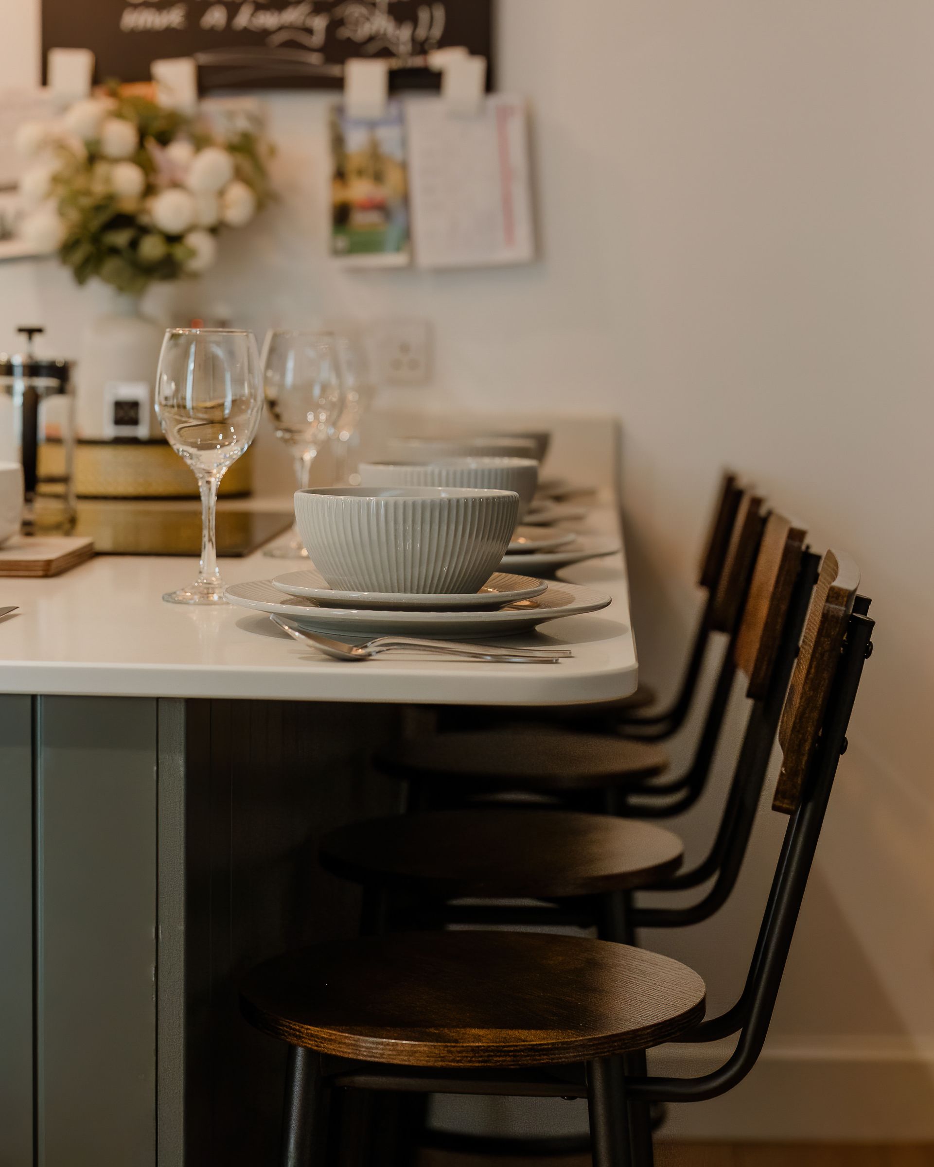 Dining table set with bowls, plates and wine glasses beside a row of chairs