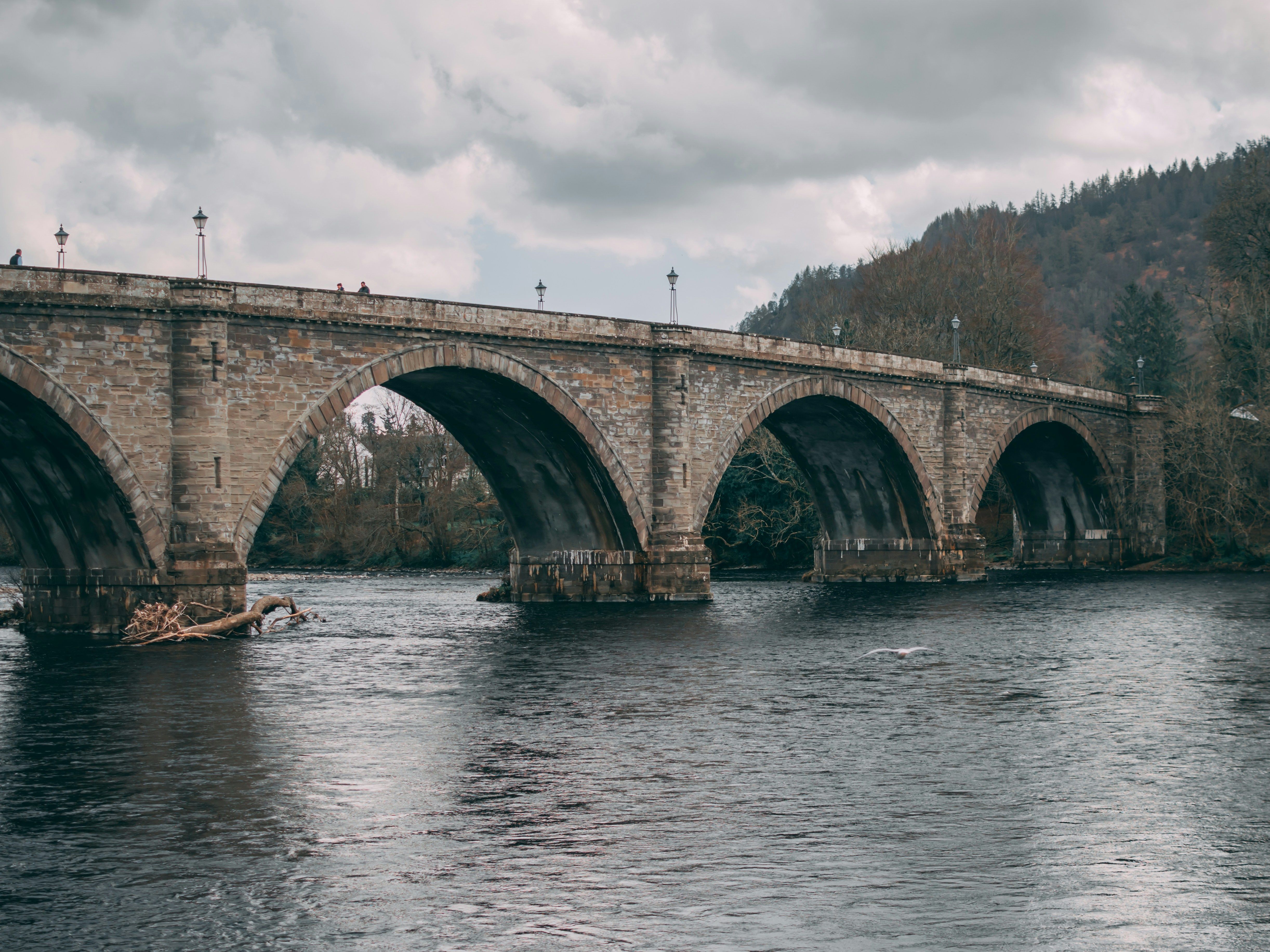 Stone arch bridge spanning a river under a cloudy sky