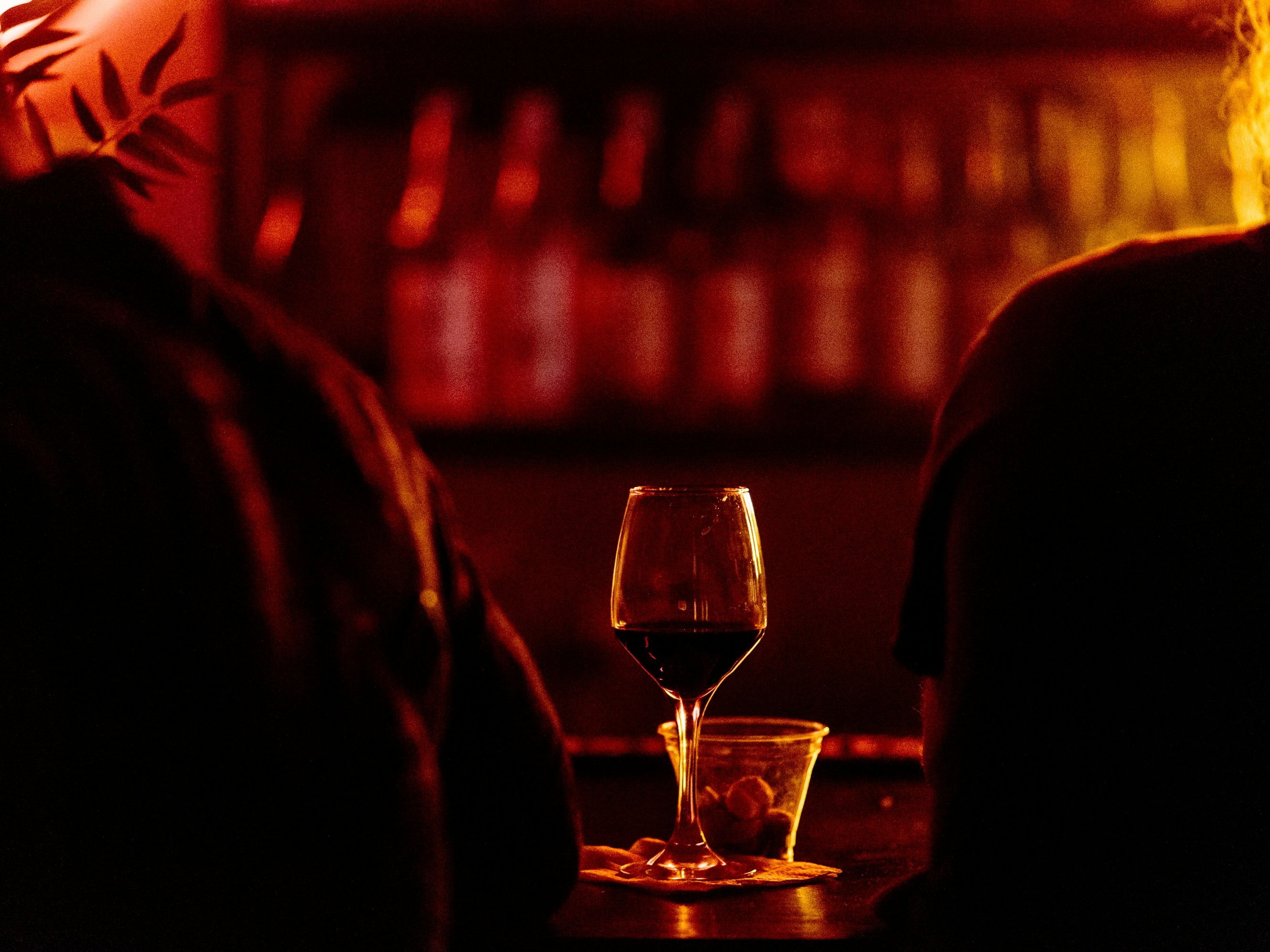 Glass of red wine on a table in a dimly lit bar with warm amber lighting