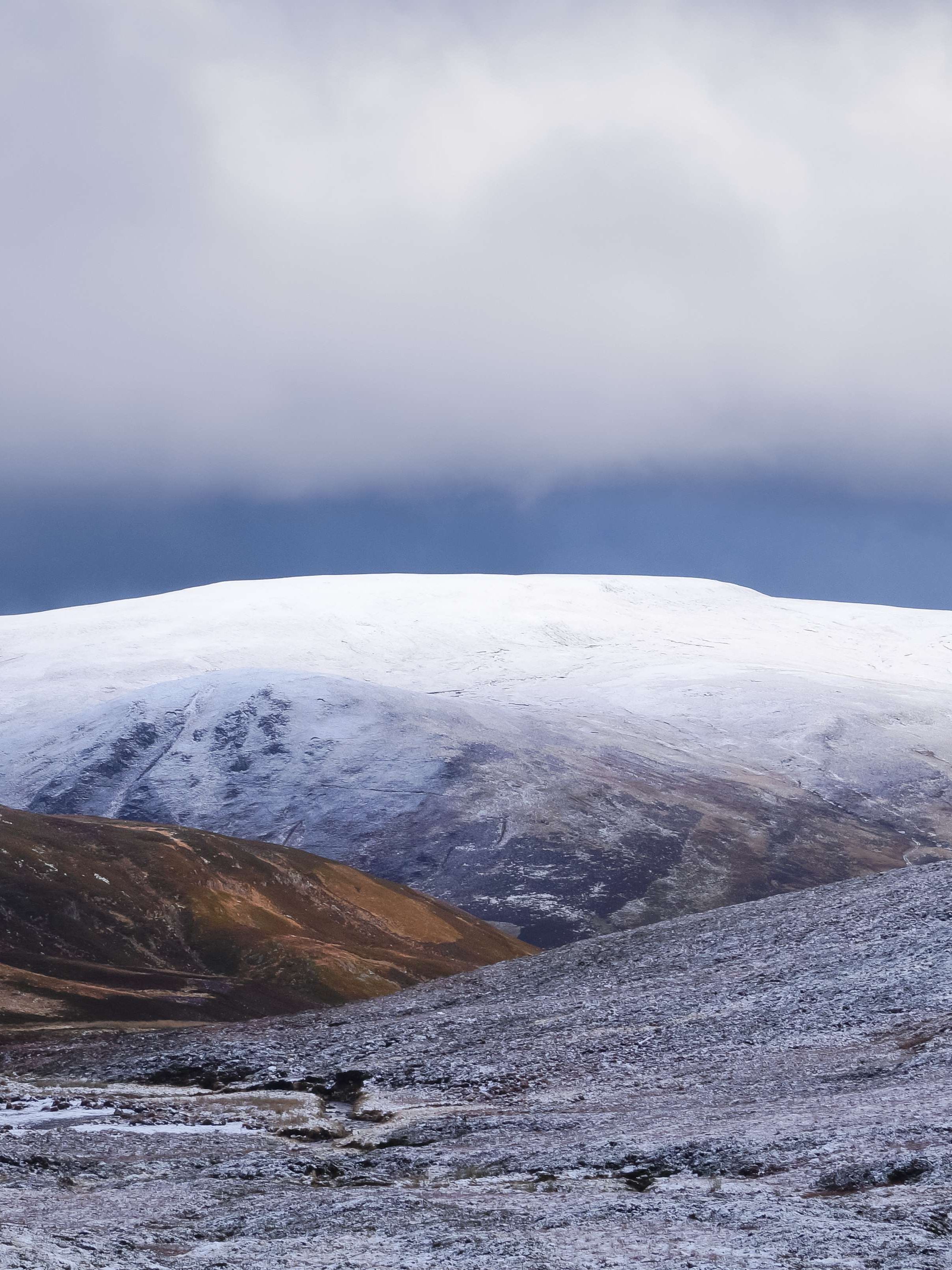 Snow-dusted hills and mountains under a cloudy sky