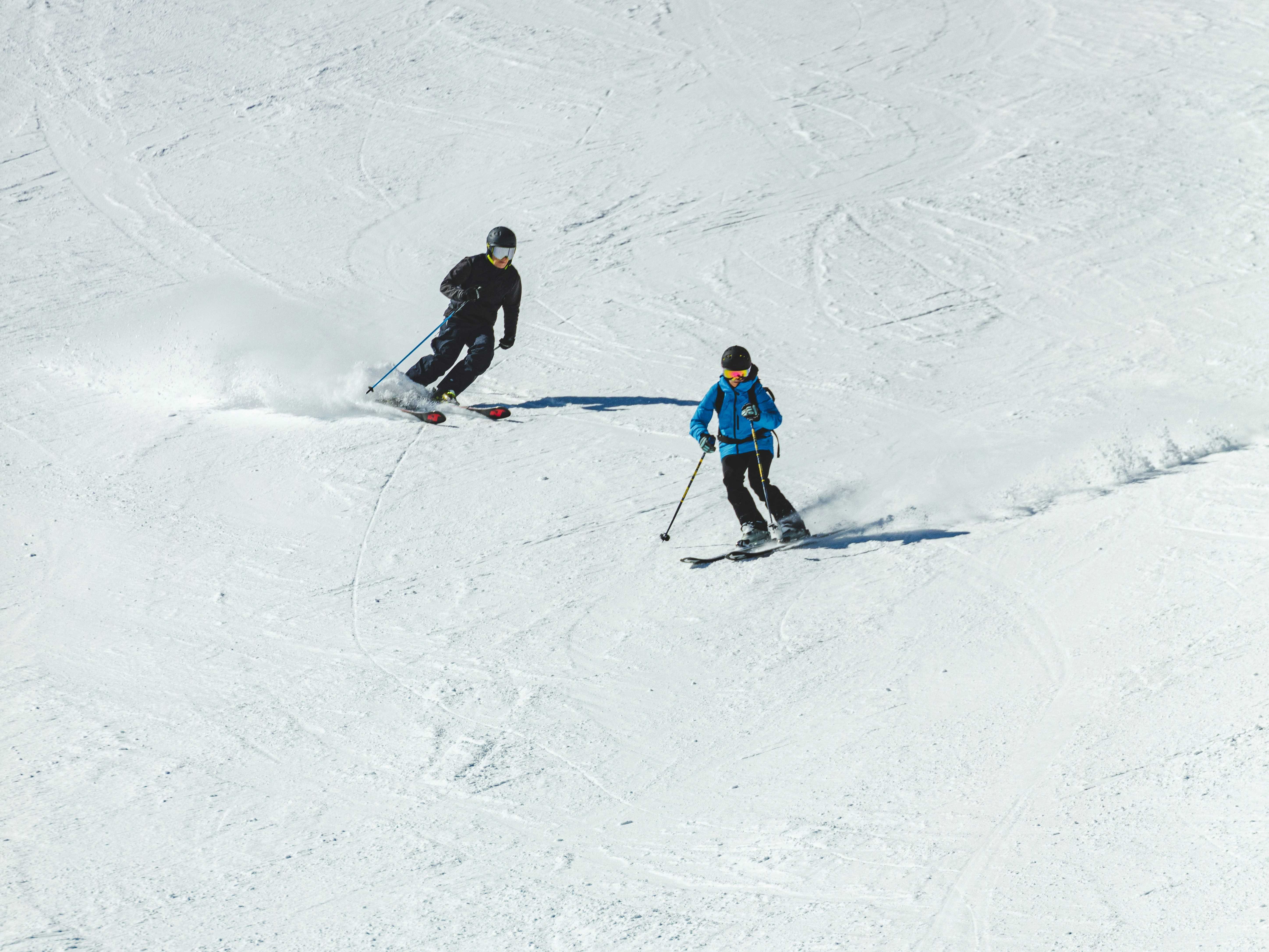 Two skiers descending a snowy slope