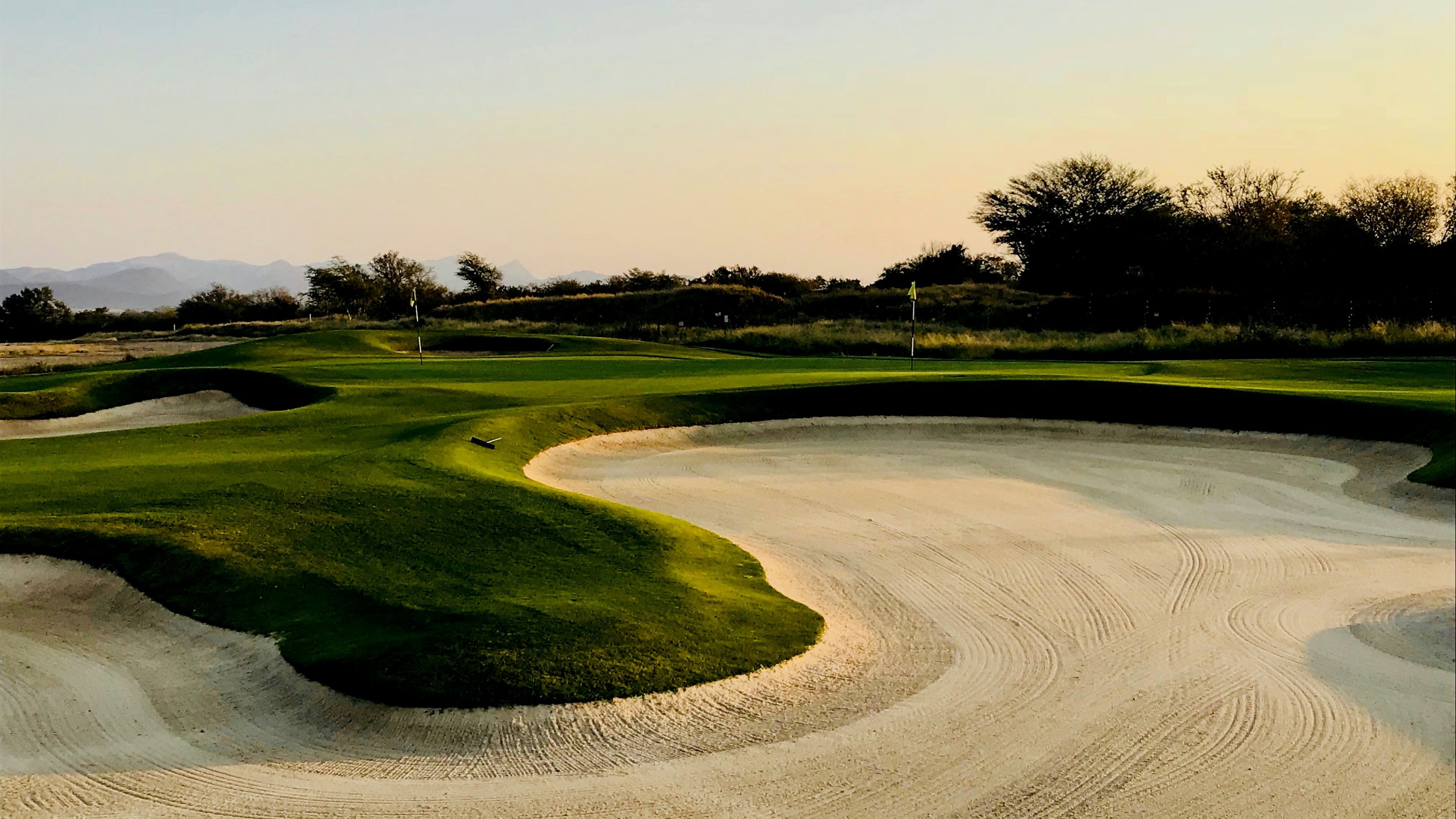 Golf course green with sand bunkers at sunset
