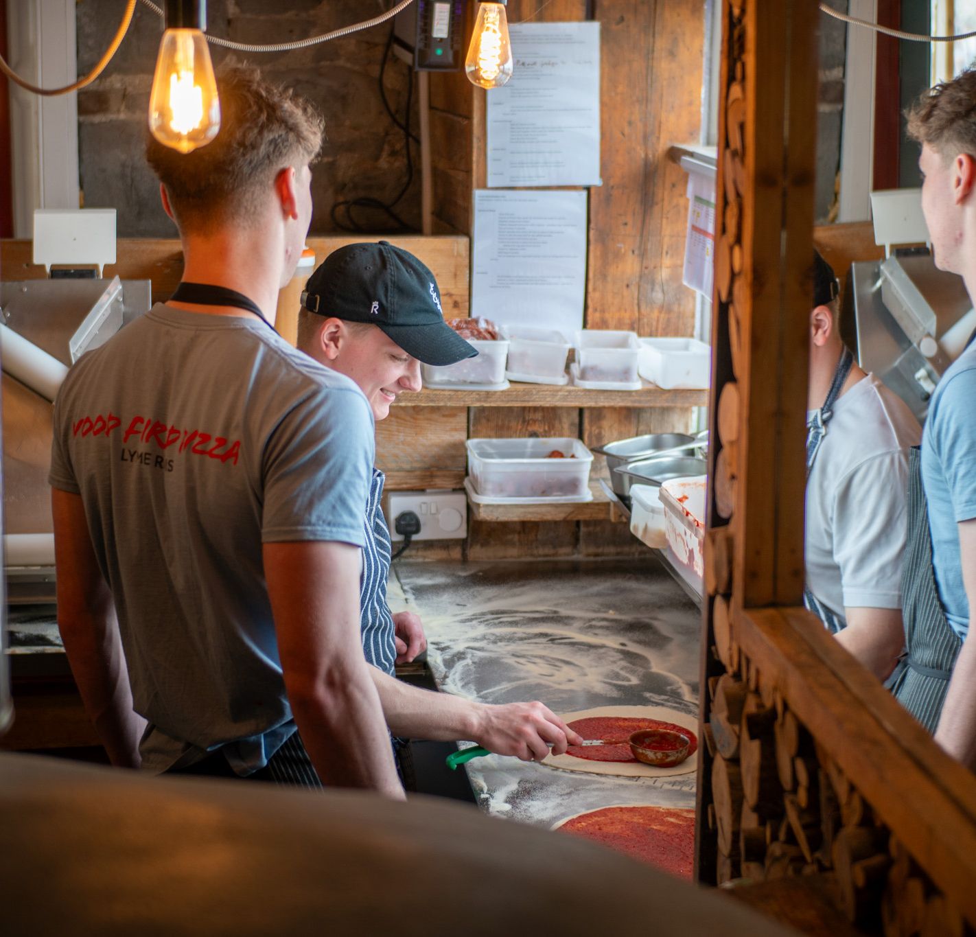 Staff preparing pizzas in a rustic wood-fired kitchen