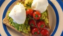 Avocado toast with poached eggs and cherry tomatoes on a plate