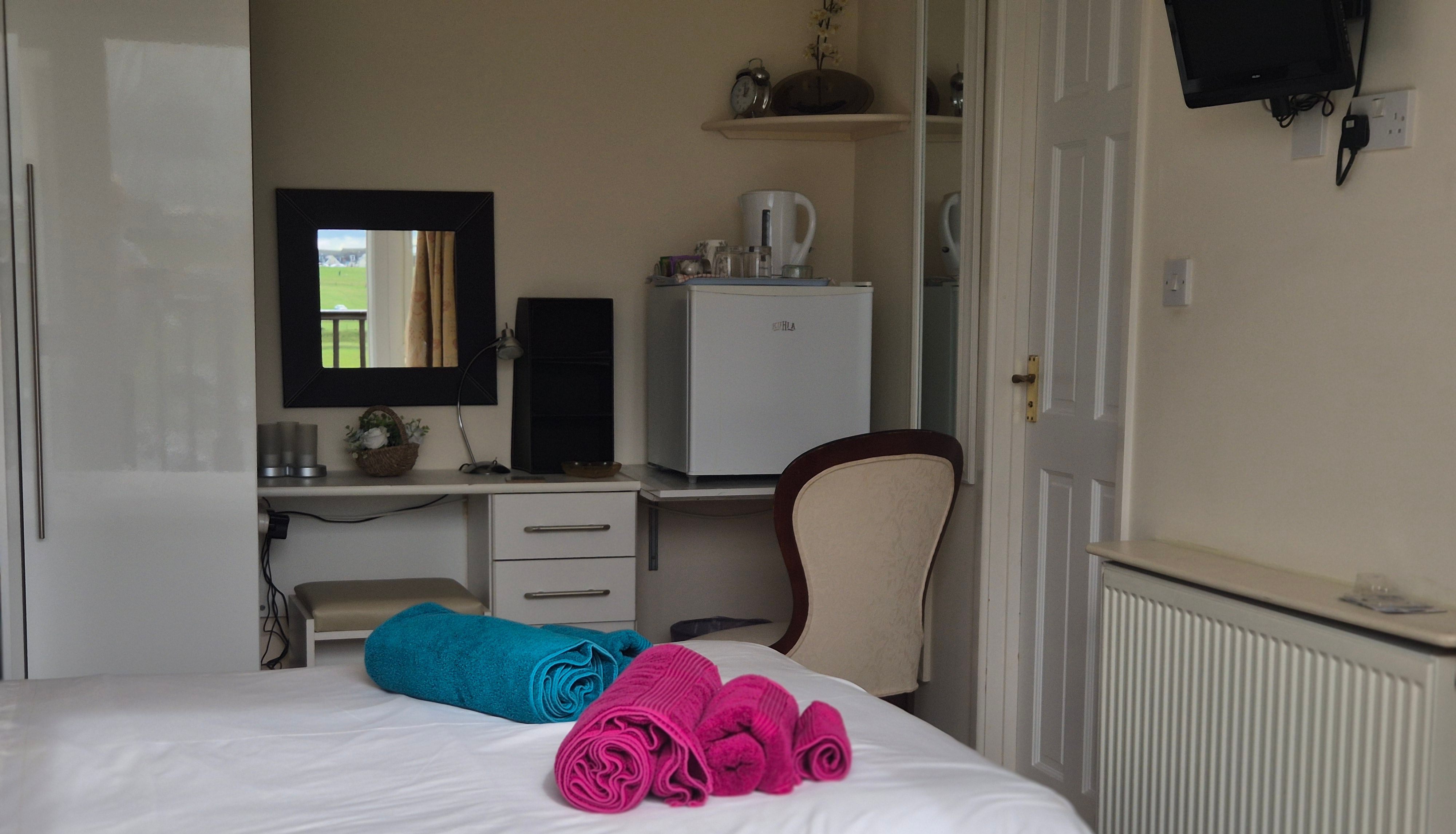 Neatly arranged bedroom with white bedding and colorful towels on the bed