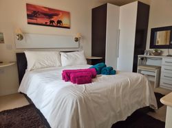 Modern bedroom with white bedding, colorful towels on the bed, and elephant wall art.