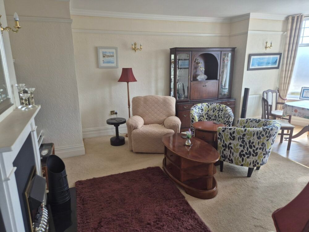 Cozy living room with armchairs, coffee tables, cabinet, and fireplace