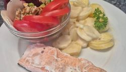 Plate with a piece of cooked salmon, creamy scalloped potatoes, and a bowl of fresh salad including tomatoes, cucumbers, beets, walnuts, and pear.