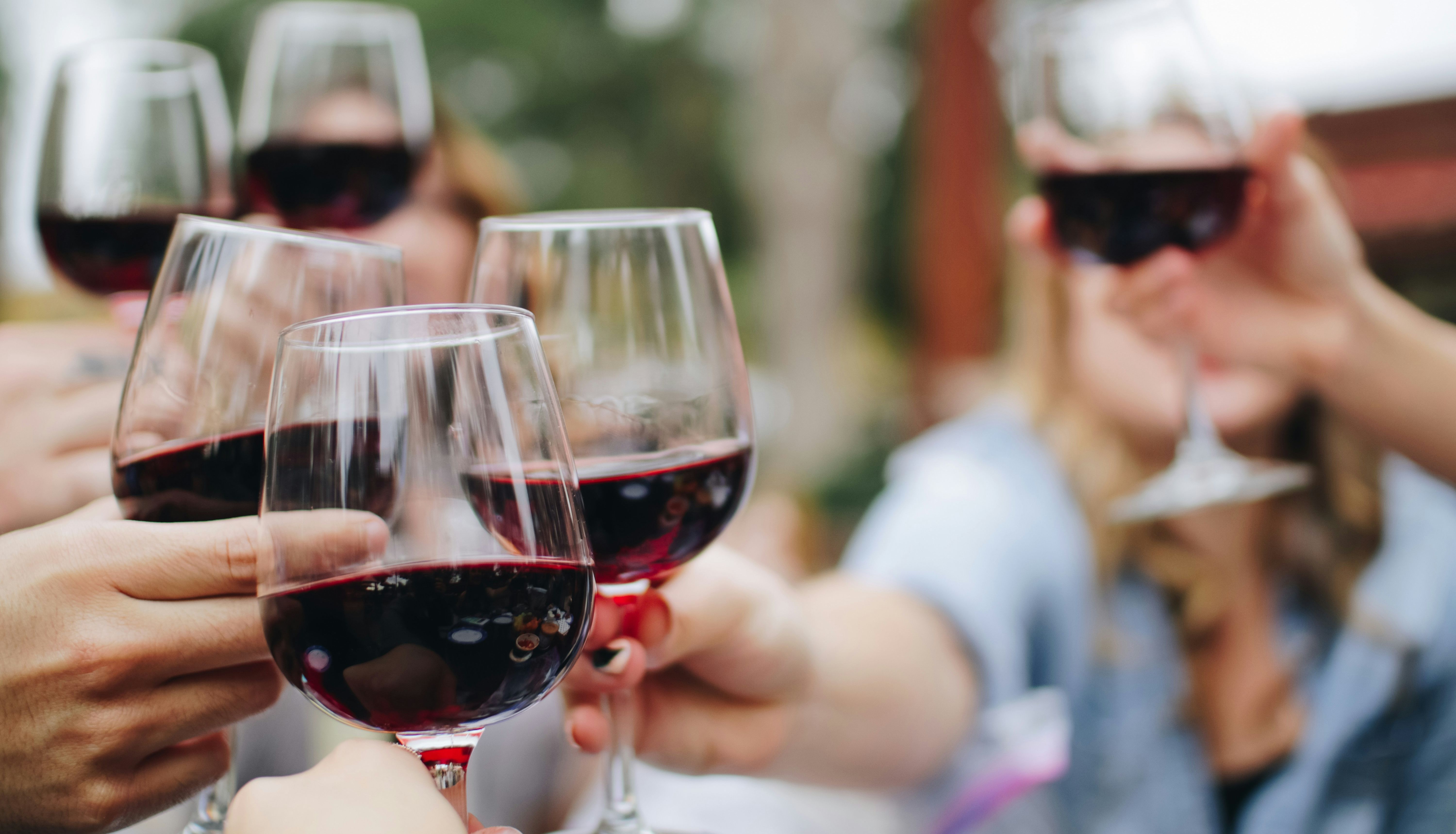 People clinking glasses of red wine together in a toast
