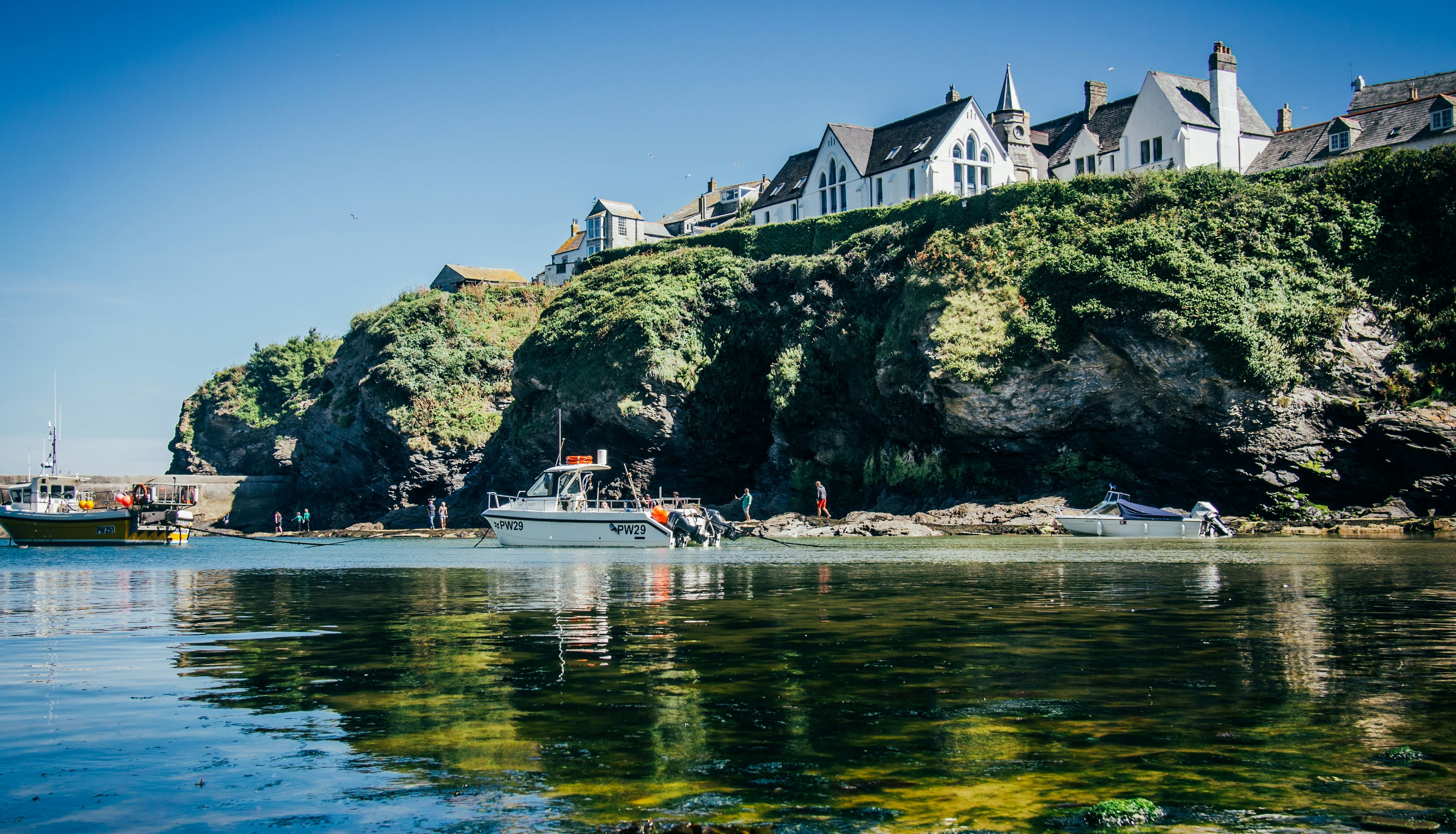 Coastal village with white houses on cliffs above the sea and boats on water