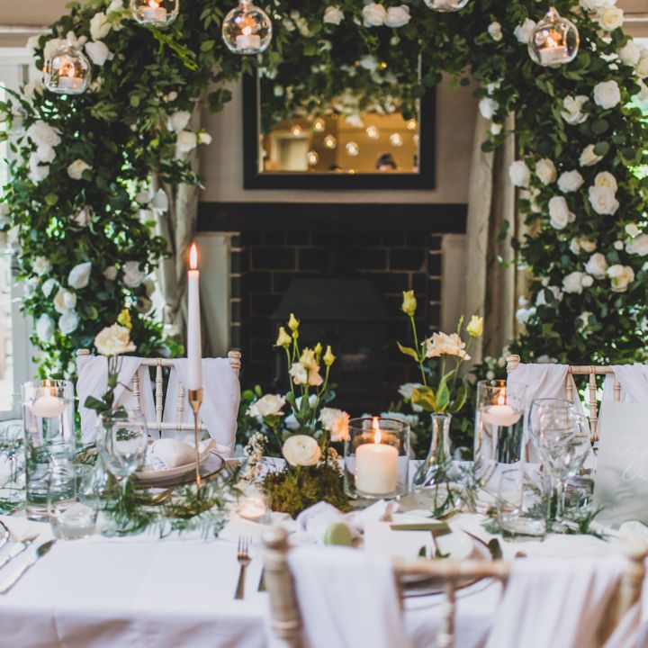 Elegant wedding table setup with floral arch and candles