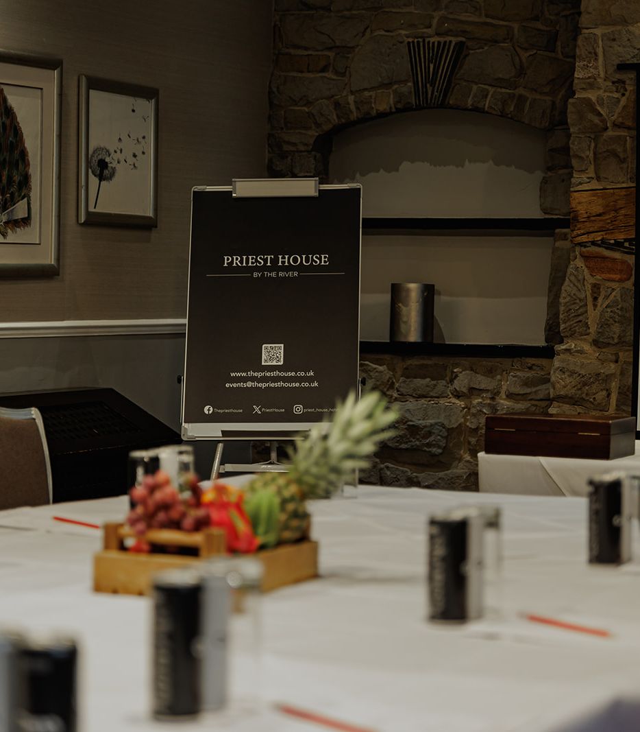 Conference room setup at Priest House with tables, chairs, refreshments, and presentation screen