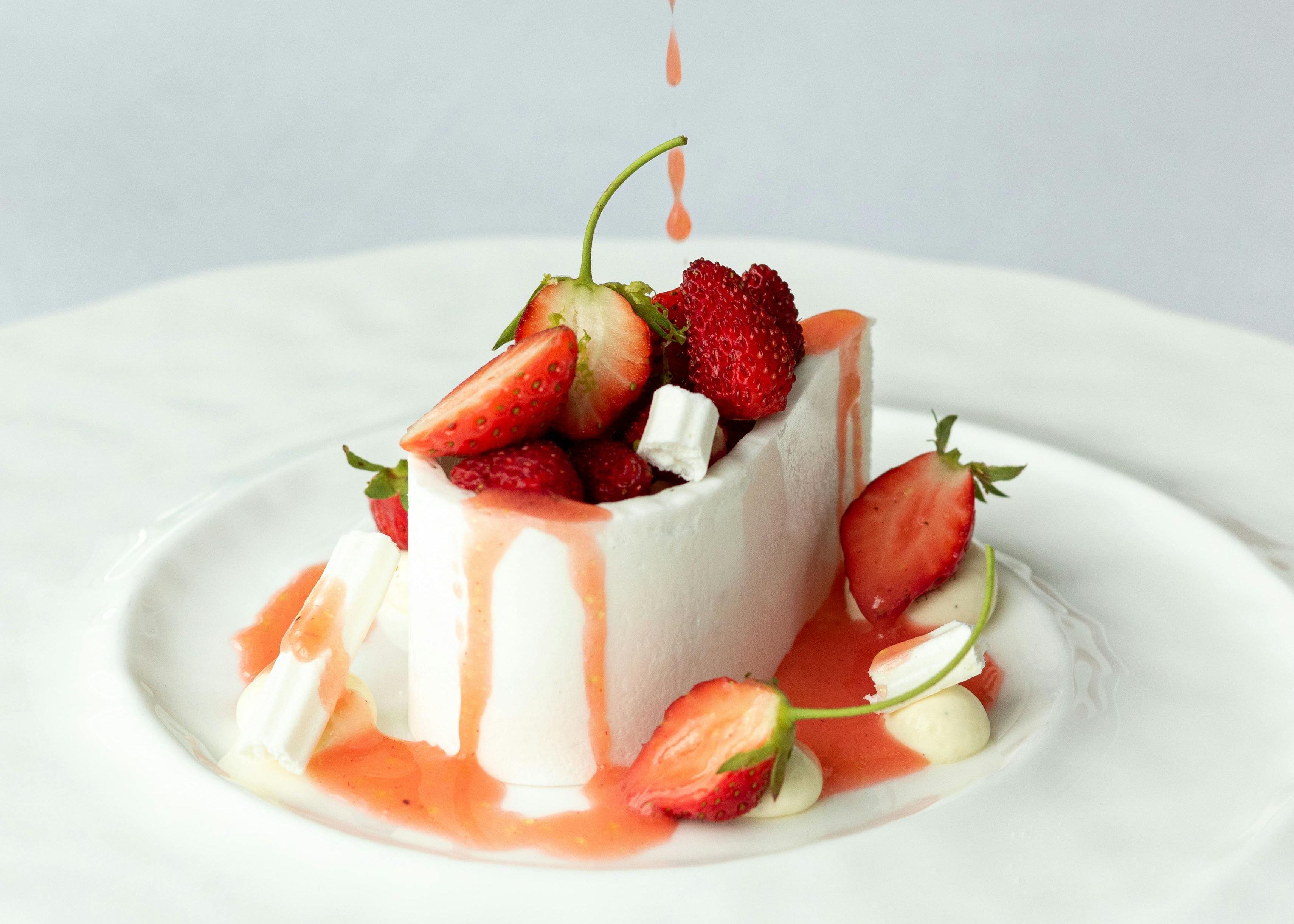 A dessert with berries and sauce being poured on top