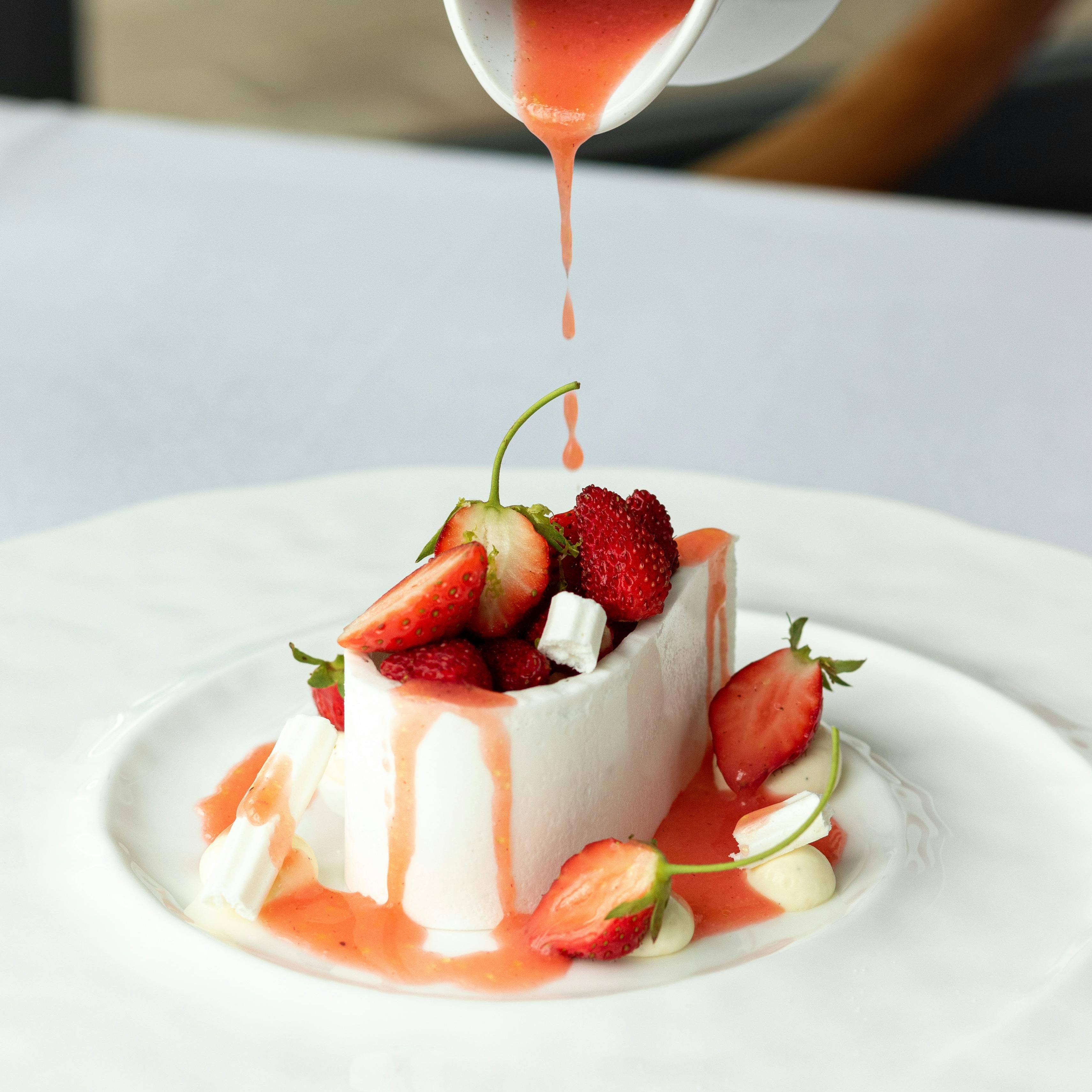 A dessert with berries and sauce being poured on top