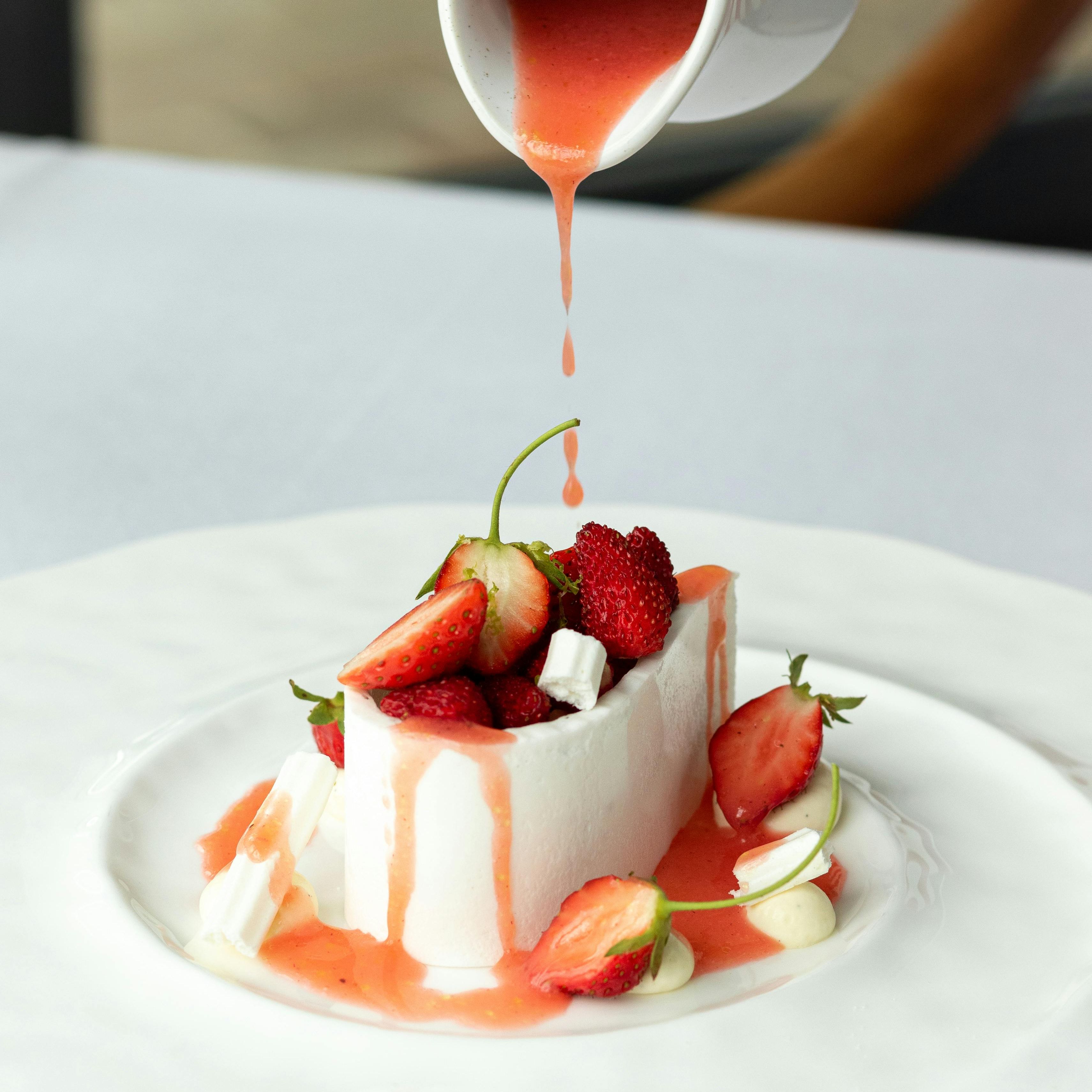 A dessert with berries and sauce being poured on top