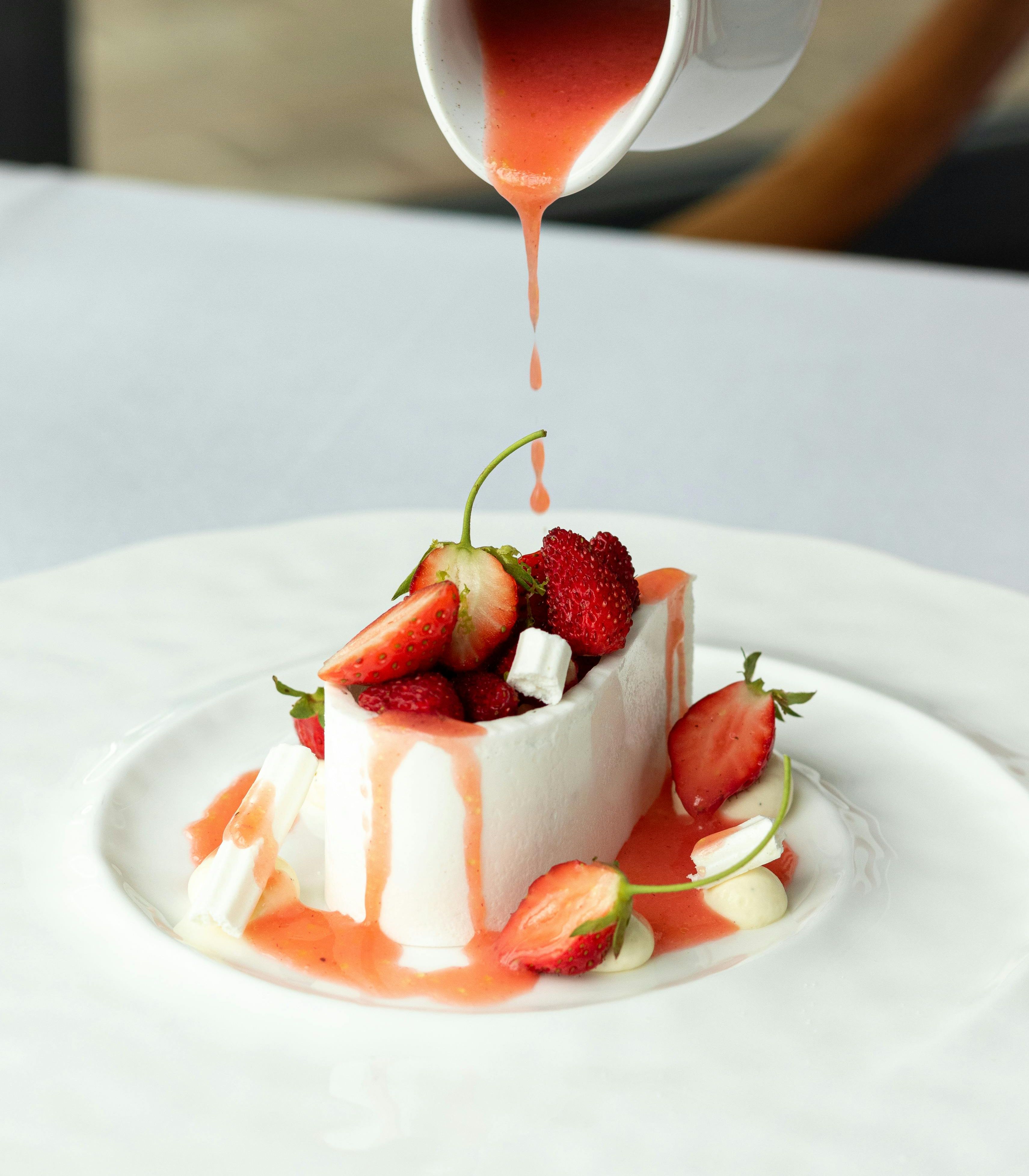 A dessert with berries and sauce being poured on top