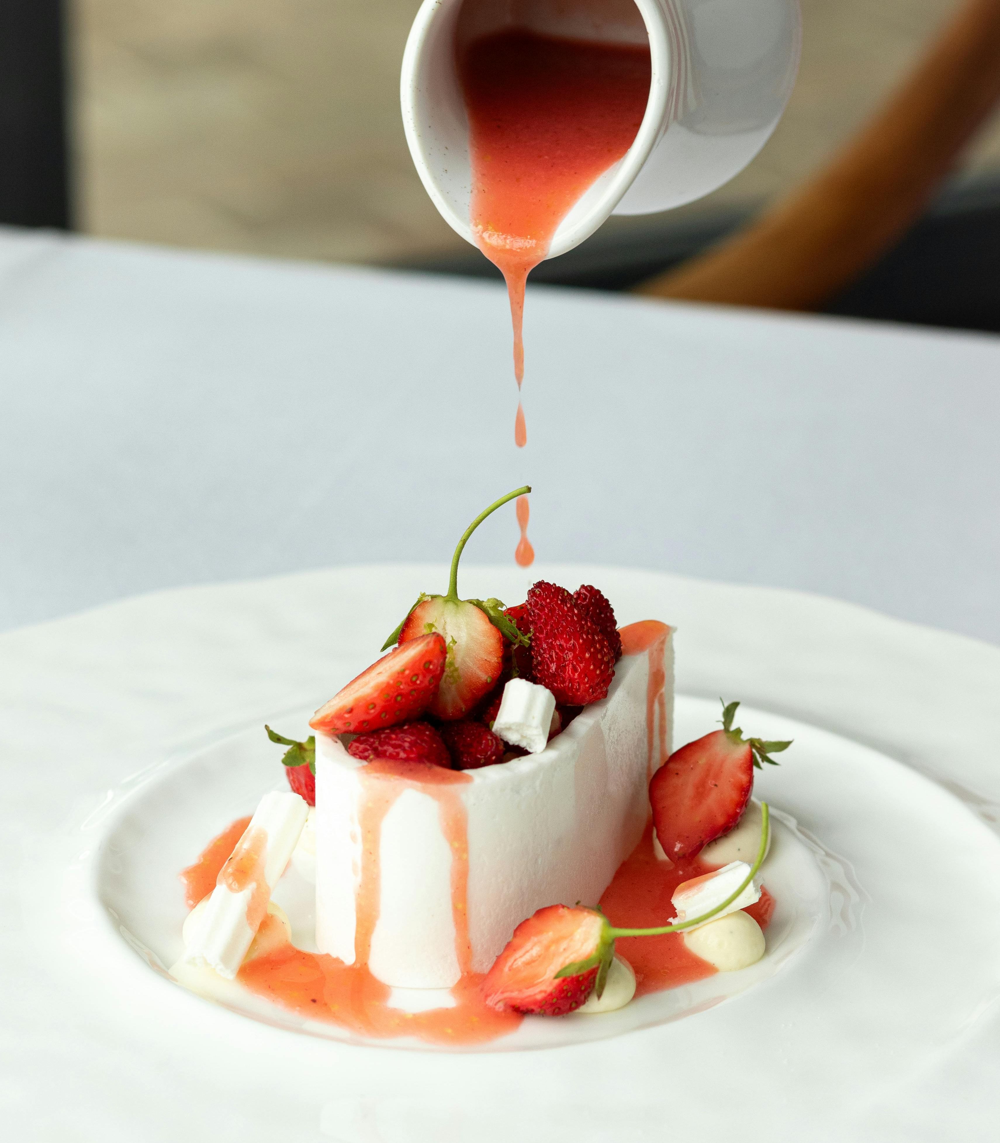 A dessert with berries and sauce being poured on top
