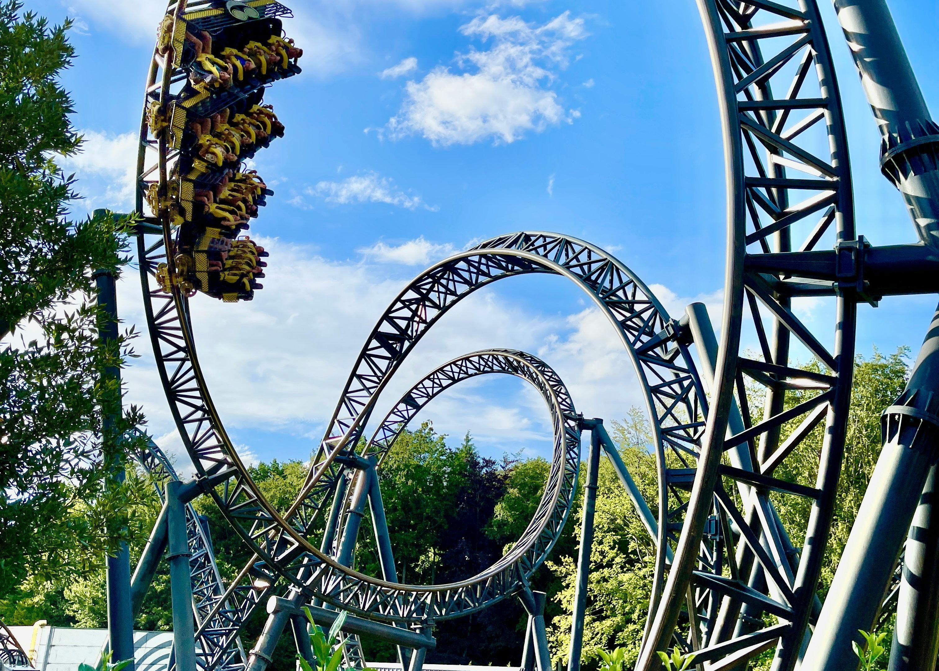 Roller coaster looping with riders under a blue sky