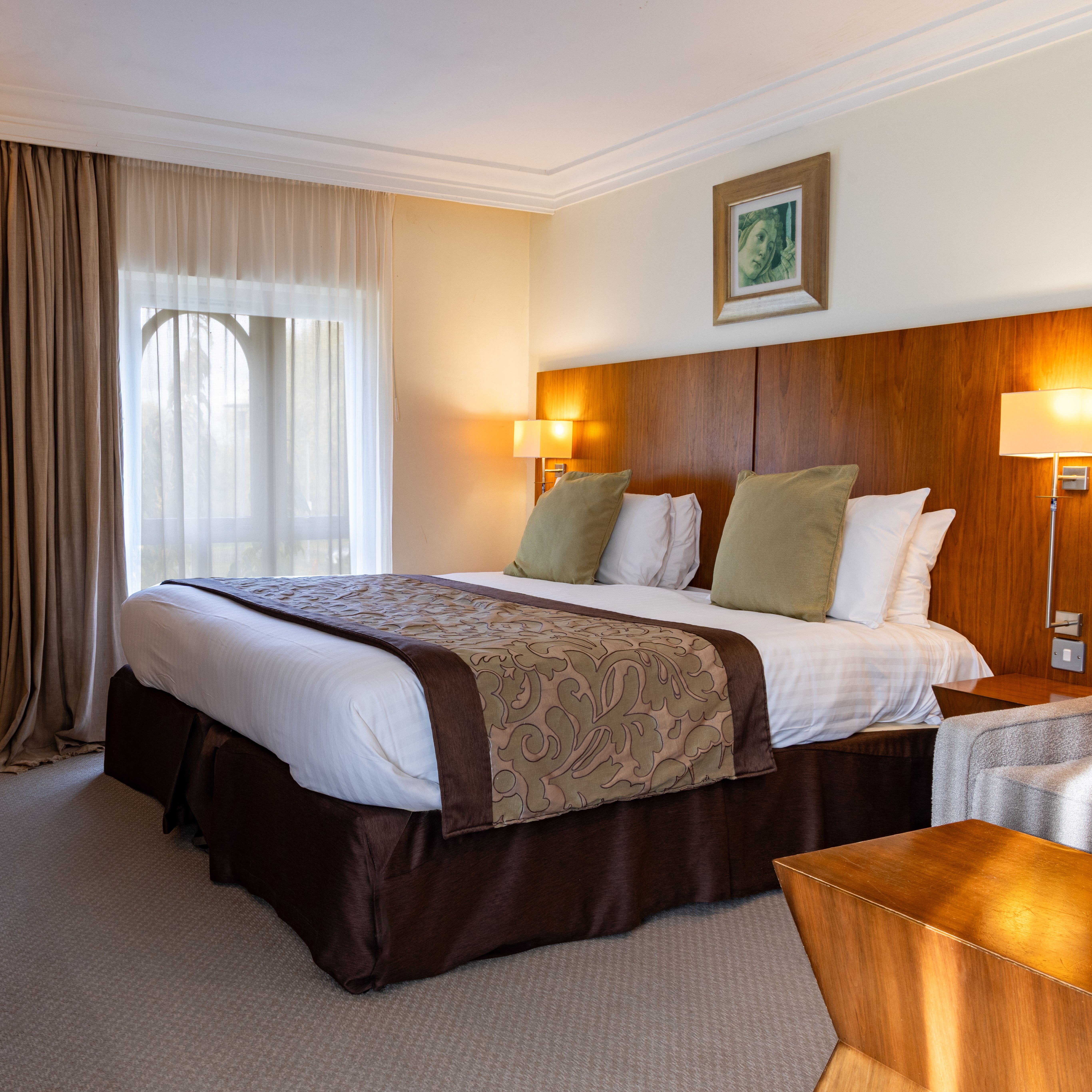 Deluxe hotel room with a large bed, wooden furniture, desk, and cozy lighting