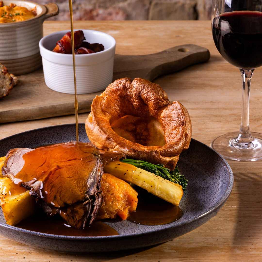 Traditional Sunday roast with beef, Yorkshire pudding, vegetables, gravy, and a glass of red wine