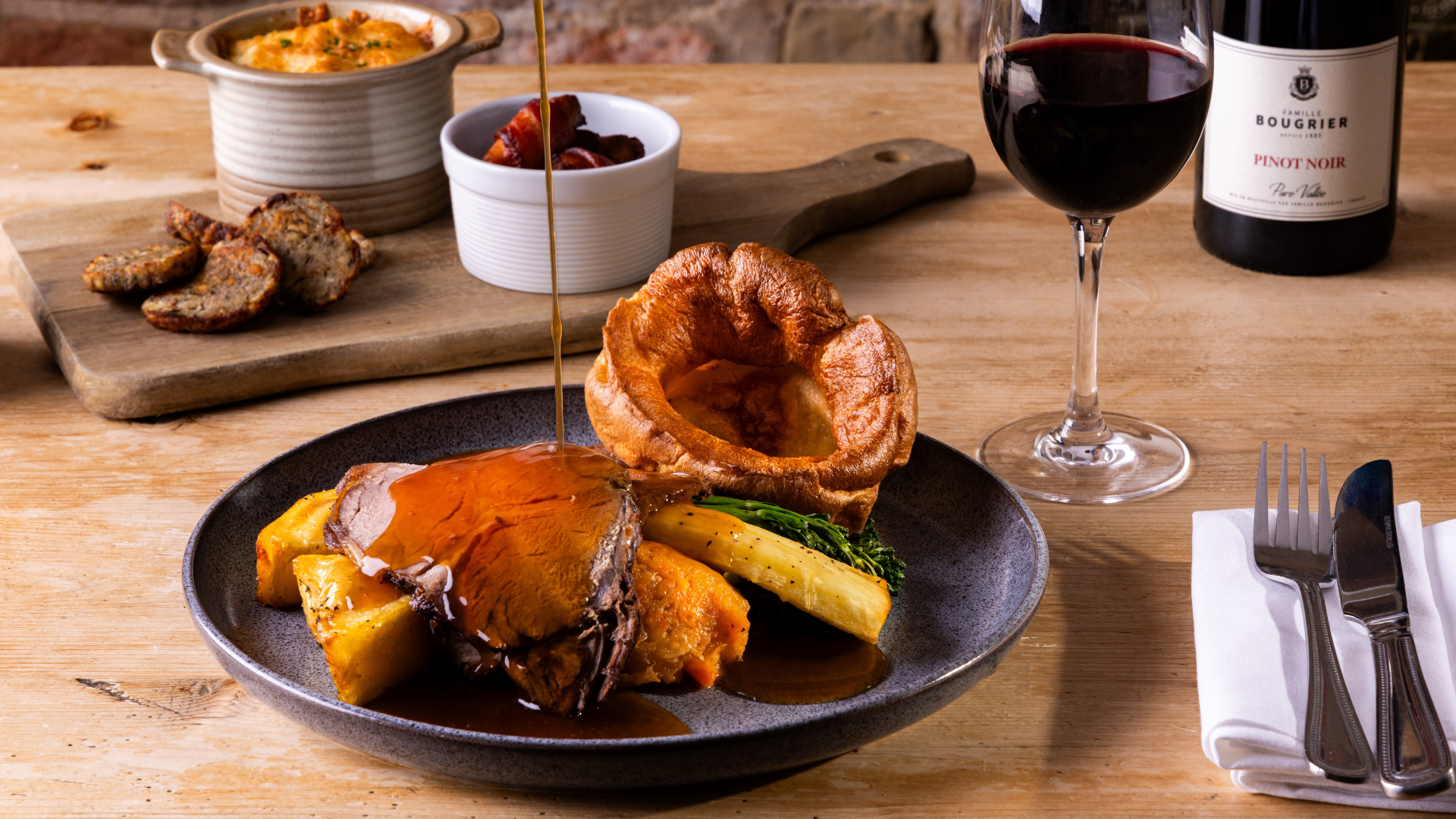 Traditional Sunday roast with beef, Yorkshire pudding, vegetables, gravy, and a glass of red wine