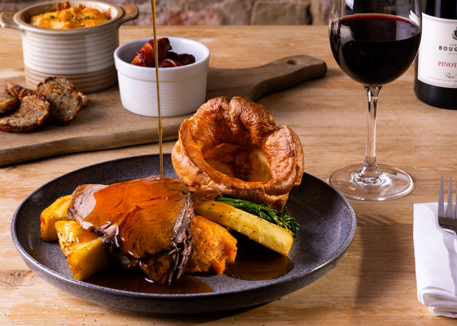 Traditional Sunday roast with beef, Yorkshire pudding, vegetables, gravy, and a glass of red wine