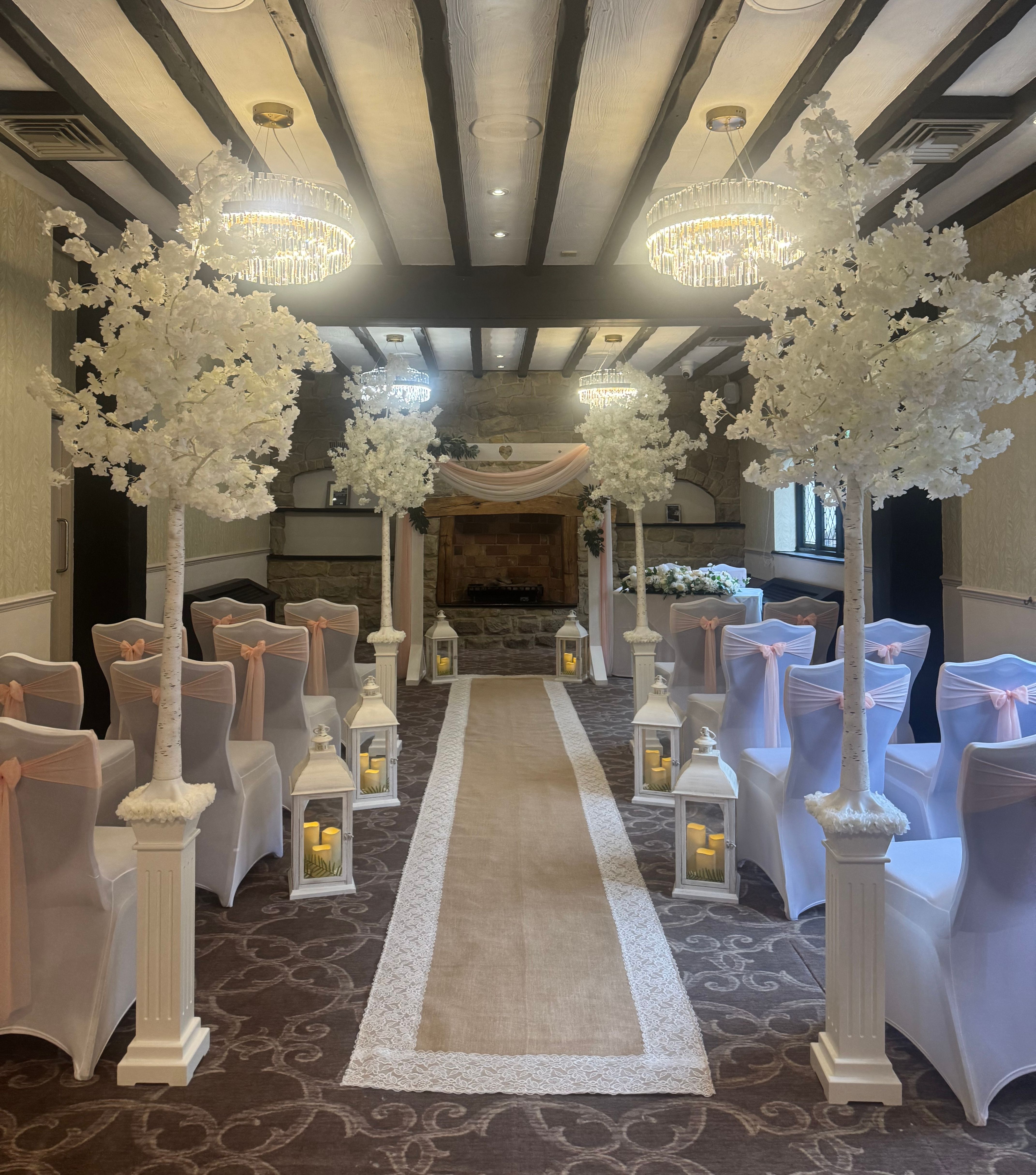 Indoor wedding ceremony setup with white flower decorations and covered chairs