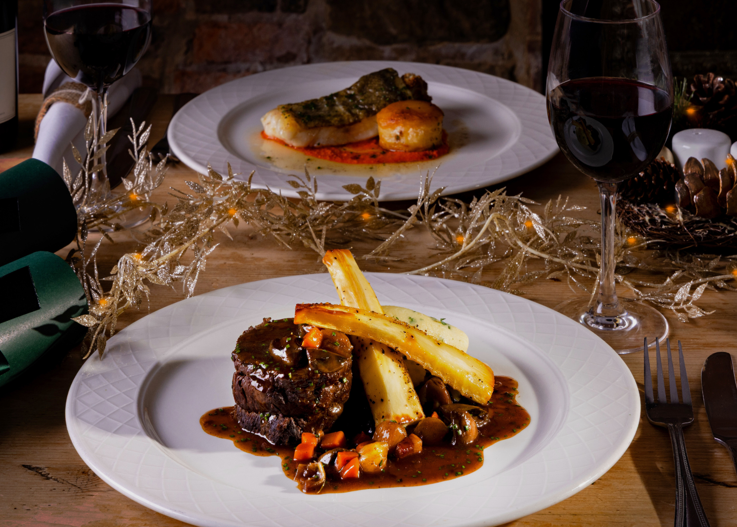 Elegant holiday dining table setting with gourmet beef dish, roasted vegetables, wine glasses, and festive decorations