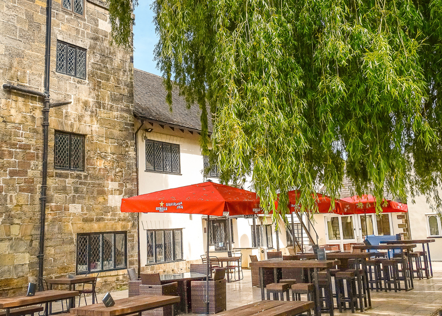 Outdoor seating area with red umbrellas outside a historic stone building