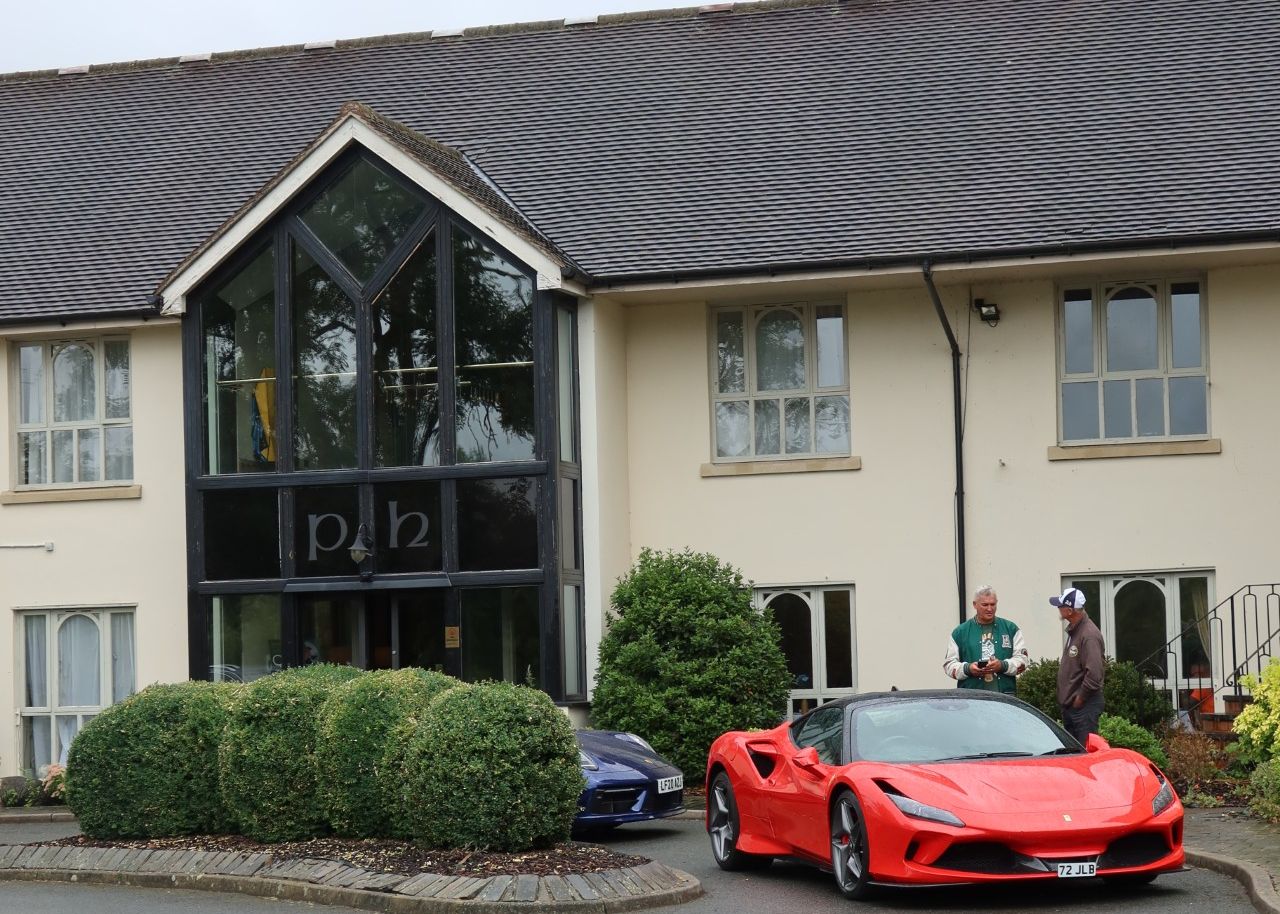 Red sports car parked in front of a building with people standing nearby