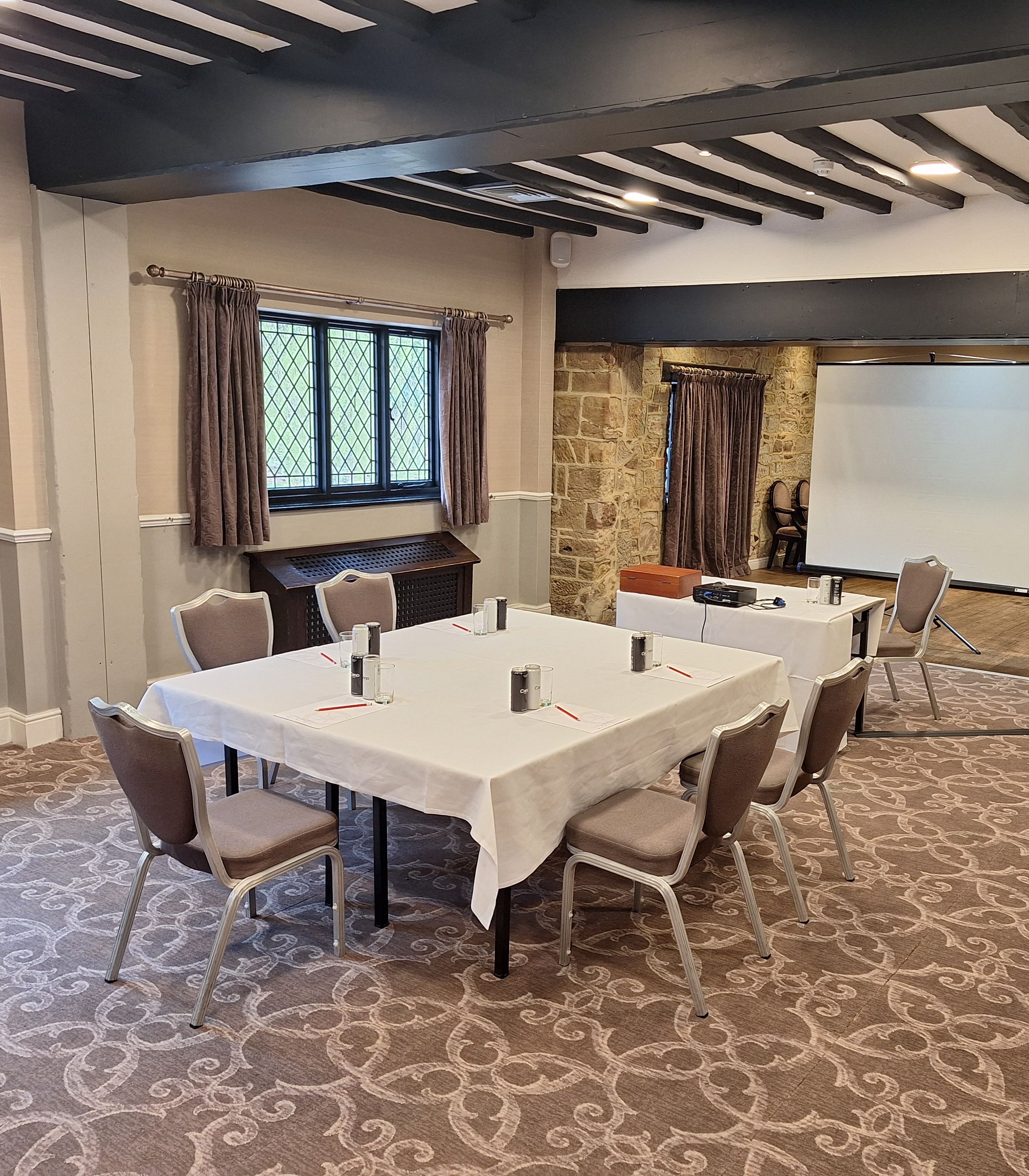 A conference room with a table, chairs, and a projector screen.